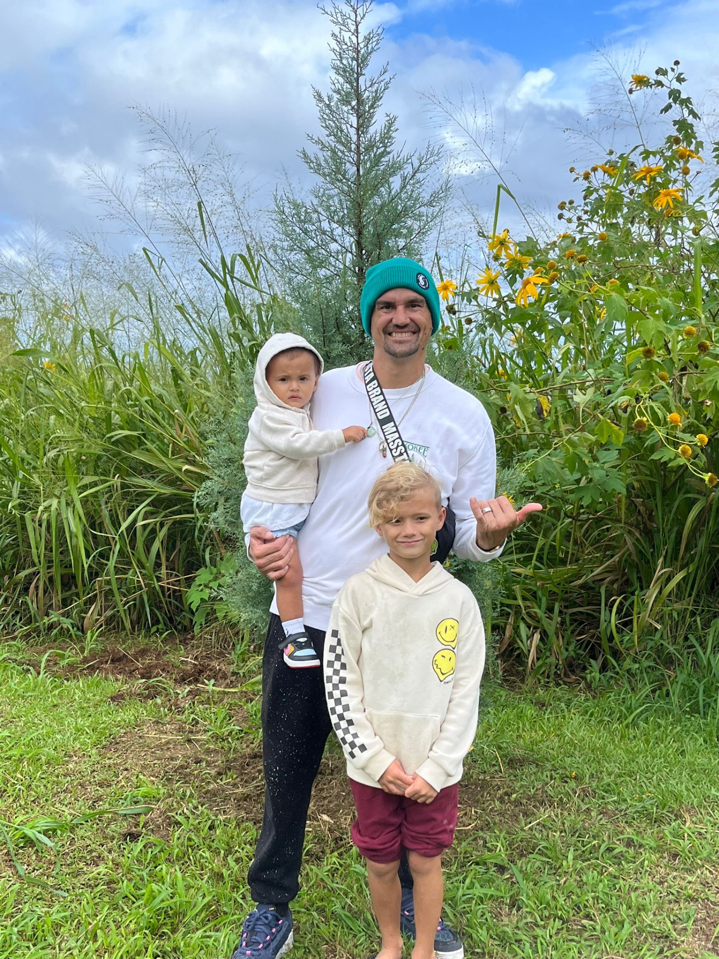 Dad with his two kids and their Christmas tree in the fields at Hamakua Christmas Tree Forest